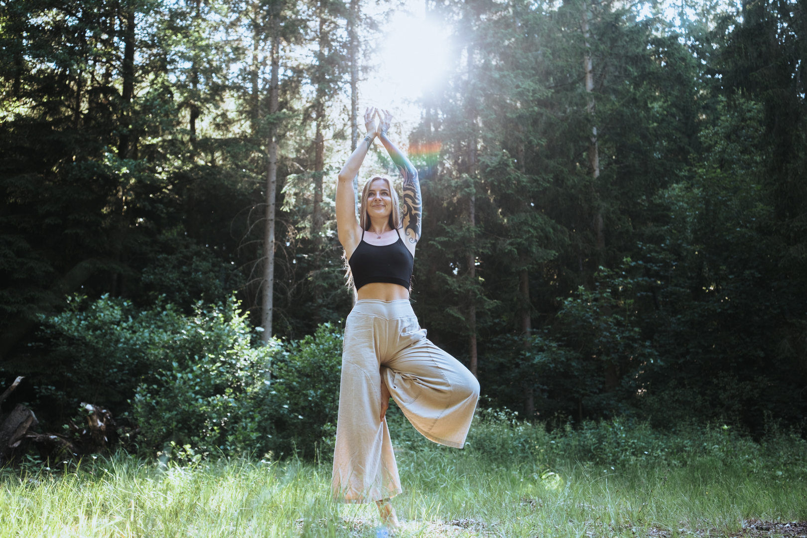 Laura Valentina in der Yoga-Baumhaltung im sonnigen Wald